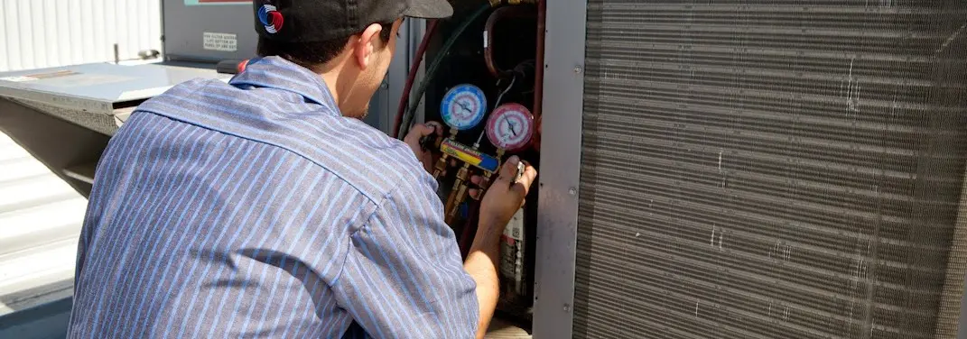 HVAC technician servicing a condenser unit in Boston